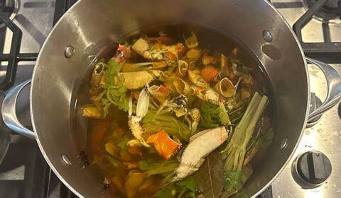 Crab stock while cooking in the pot with veggies.