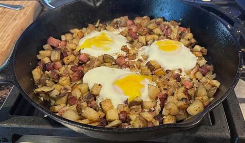 Cast iron skillet with breakfast hash on the stove.