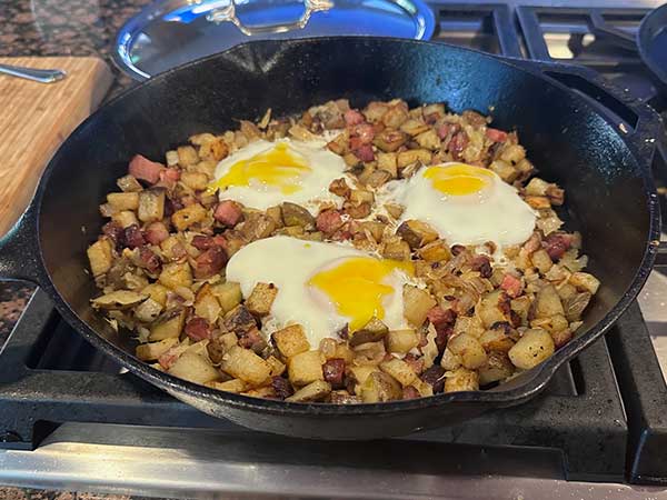 Cast iron skillet with breakfast hash on the stove.